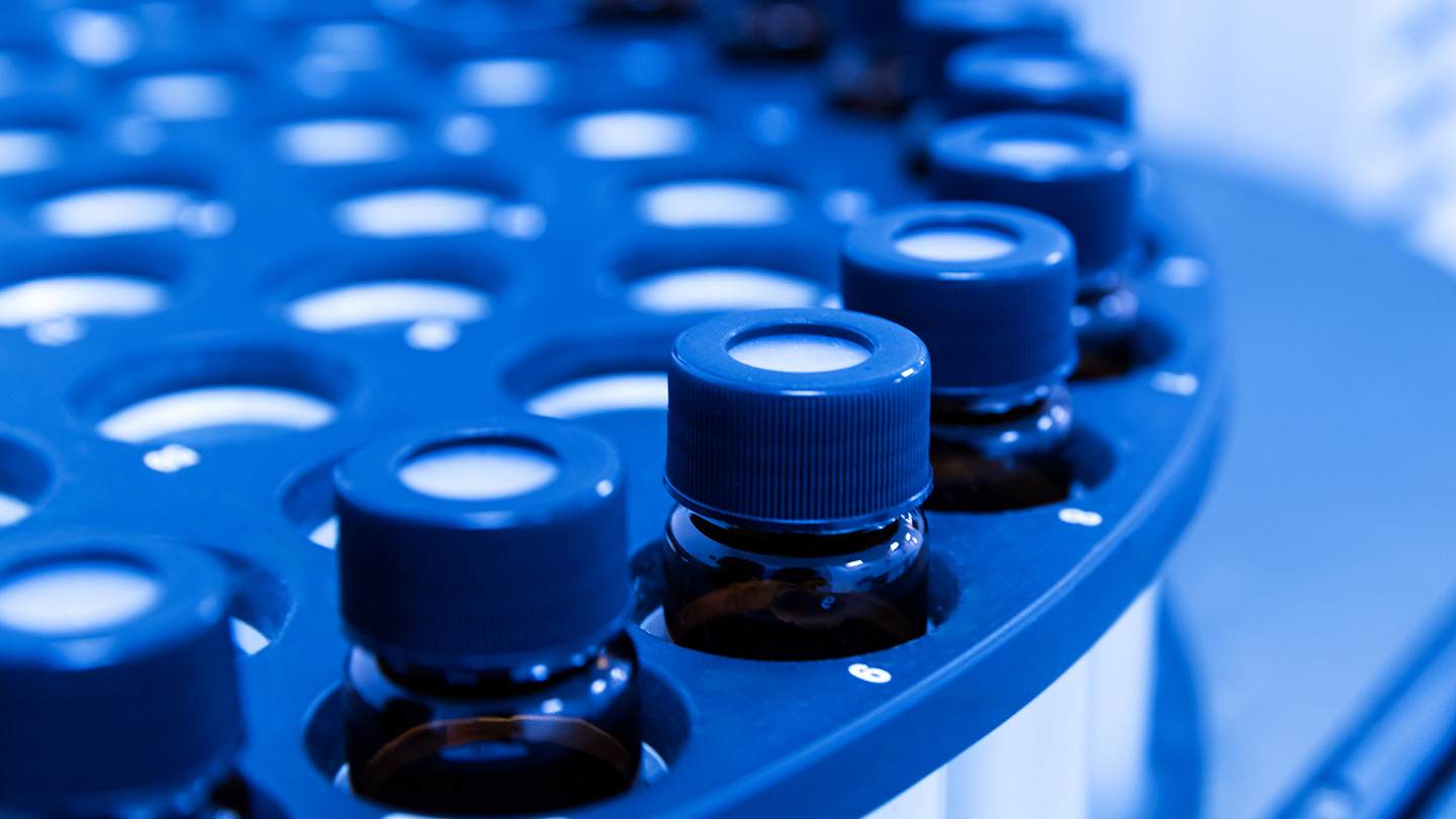 Close-up of several small, capped vials arranged in a circular holder, likely in a laboratory setting.